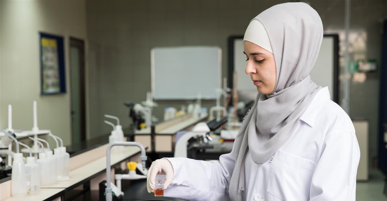 Health sciences student at Abu Dhabi University conducting a lab experiment with safety gear.
