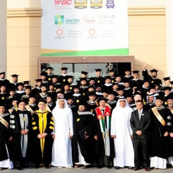 Group graduation photo at Abu Dhabi University with faculty and students in academic gowns.