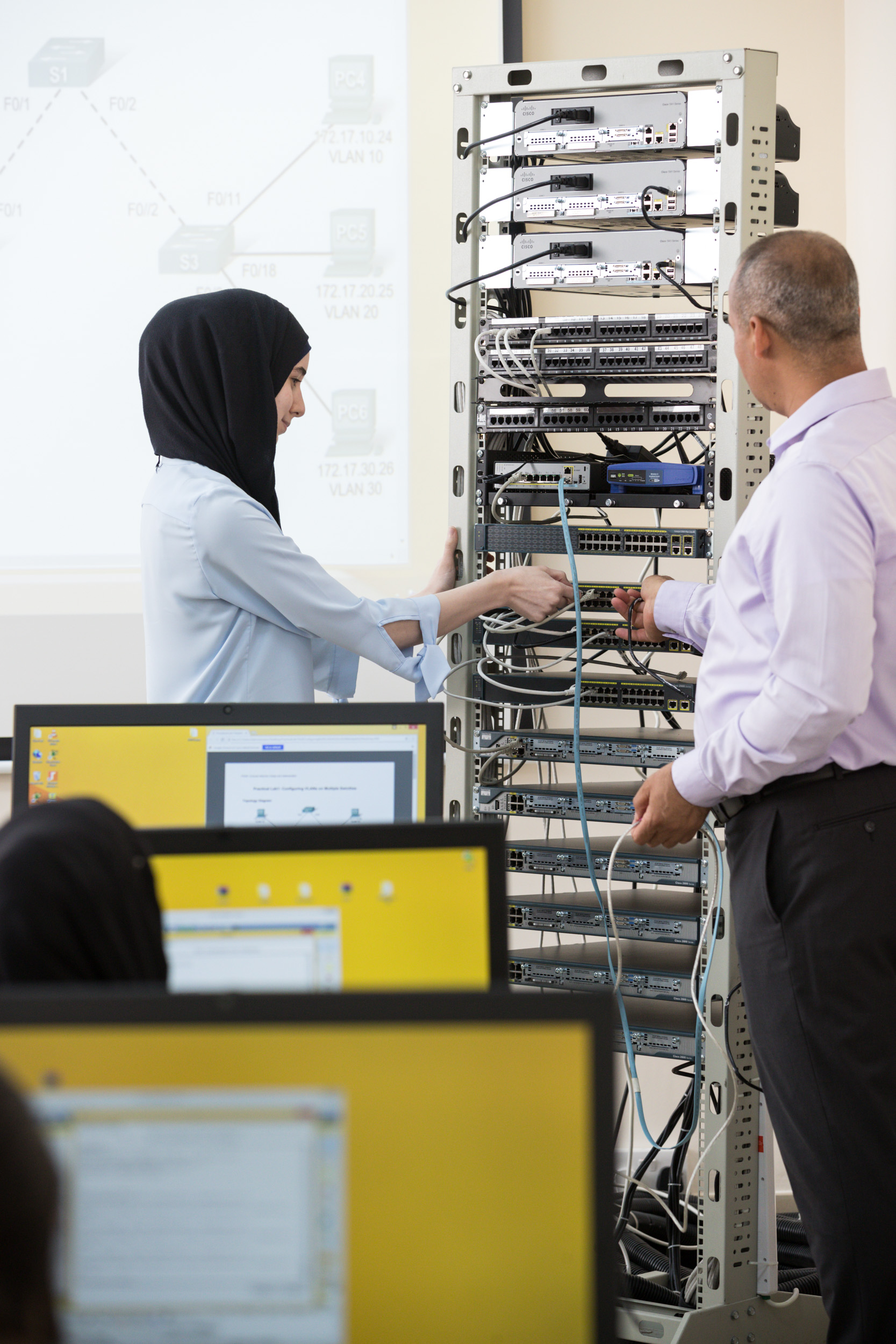 IT students working on a server rack during a practical networking lab session at Abu Dhabi University.