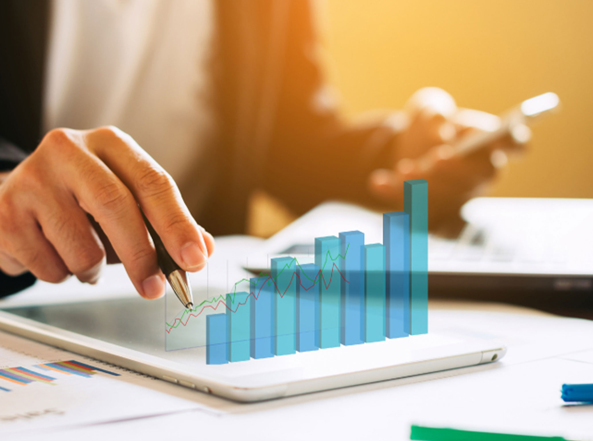 Businessperson analyzing a rising 3D bar chart on a tablet using a pen and smartphone.